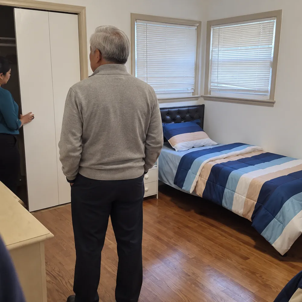 A visitor looking at a single bedroom with a blue bedspread