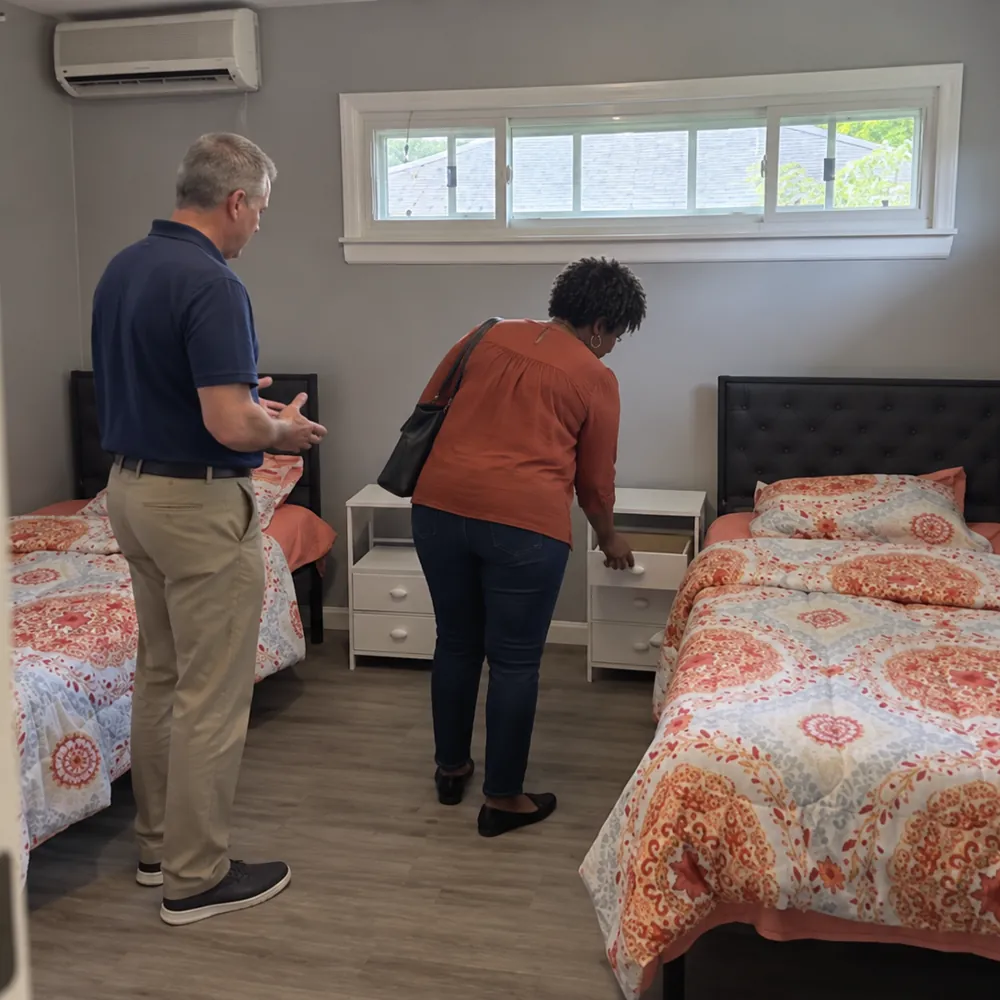 A couple looking at a shared bedroom with two beds