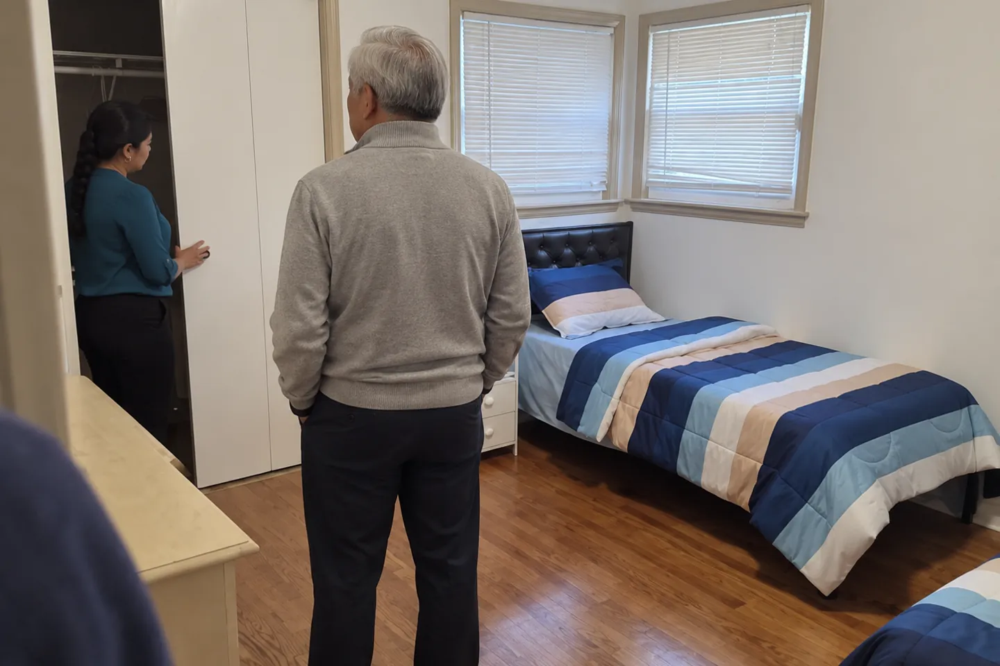 A staff member showing a visitor the closet in a single bedroom