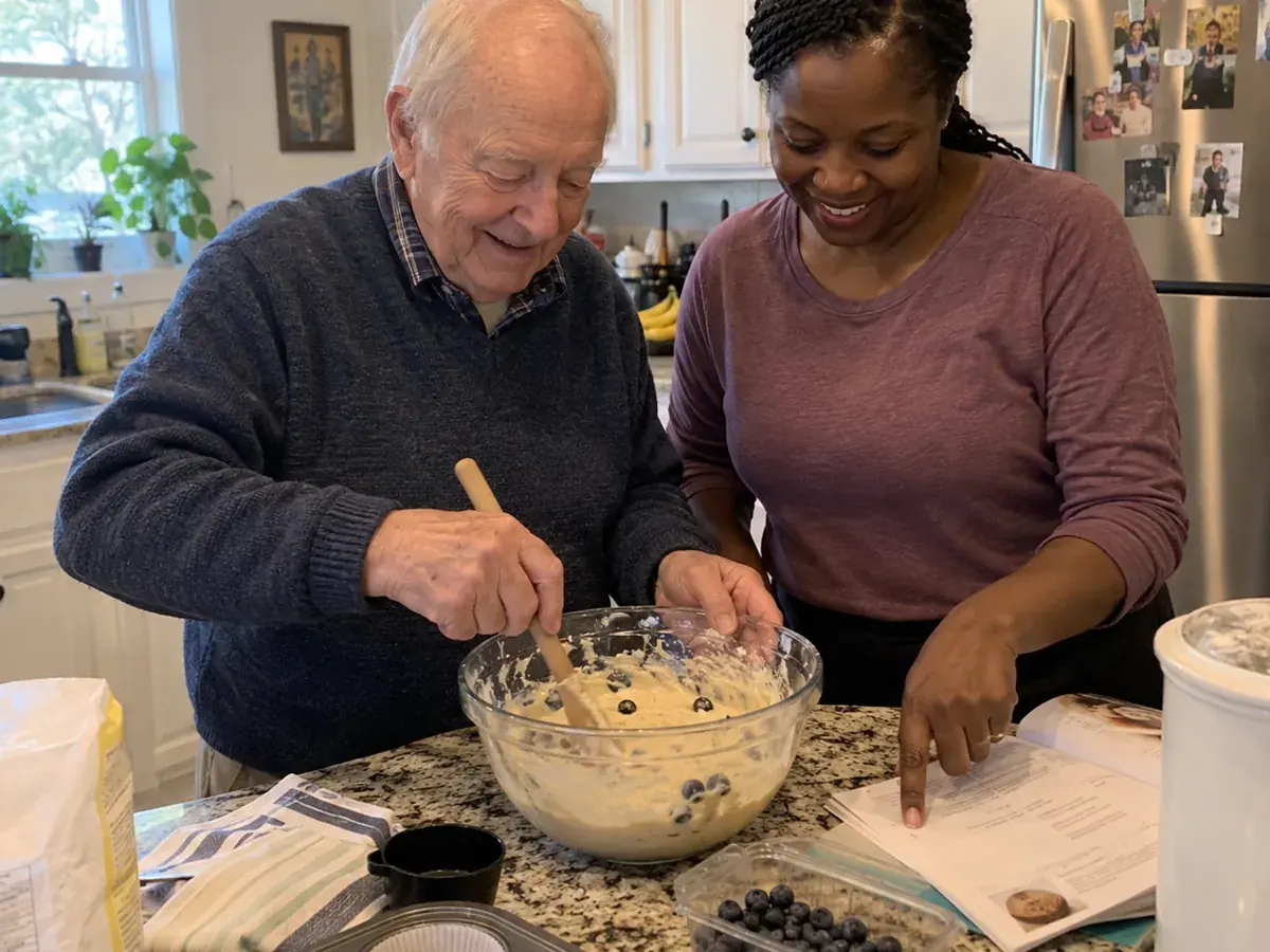 A resident baking with a caregiver in the kitchen